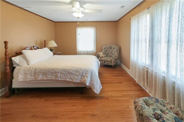 bedroom featuring light hardwood / wood-style floors, ornamental molding, and ceiling fan