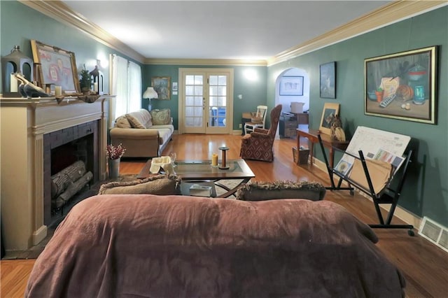 living room featuring crown molding, a fireplace, french doors, and hardwood / wood-style flooring