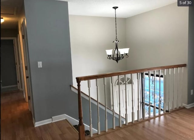 staircase with wood-type flooring and a notable chandelier