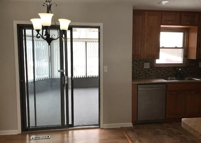 kitchen with sink, dark wood-type flooring, stainless steel dishwasher, a chandelier, and decorative backsplash