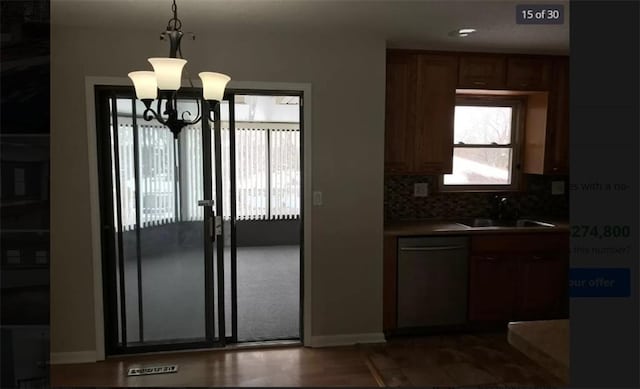 kitchen with decorative backsplash, stainless steel dishwasher, sink, pendant lighting, and an inviting chandelier