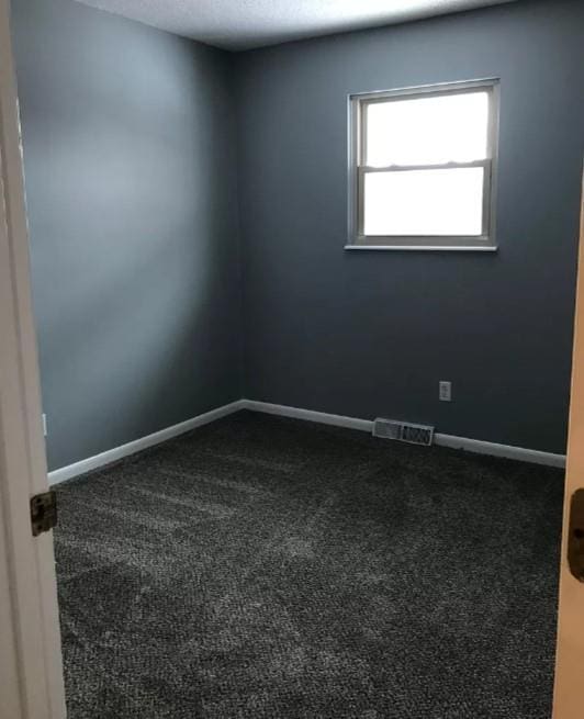 spare room featuring dark colored carpet