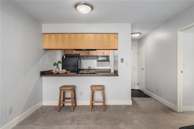 kitchen featuring a breakfast bar area, kitchen peninsula, carpet floors, and black appliances