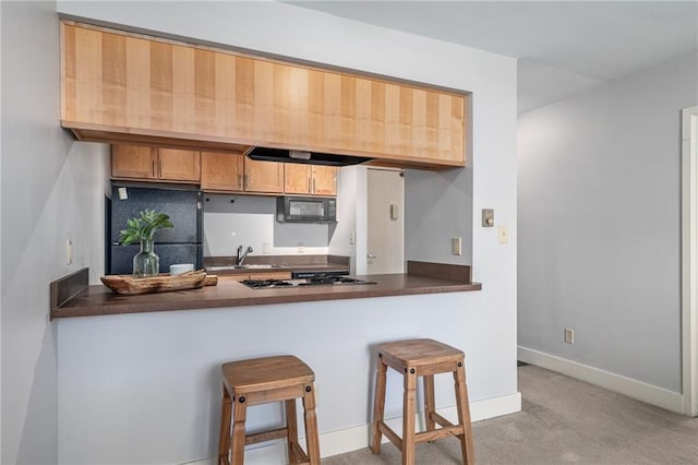 kitchen featuring sink, backsplash, kitchen peninsula, a kitchen bar, and black appliances