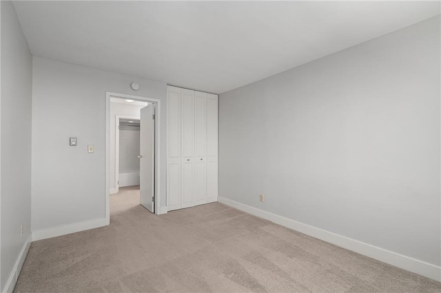 unfurnished bedroom featuring light colored carpet and a closet