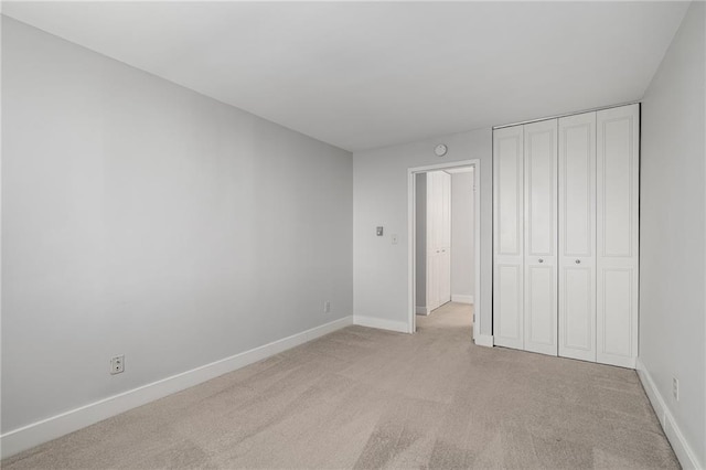 unfurnished bedroom with a closet and light colored carpet