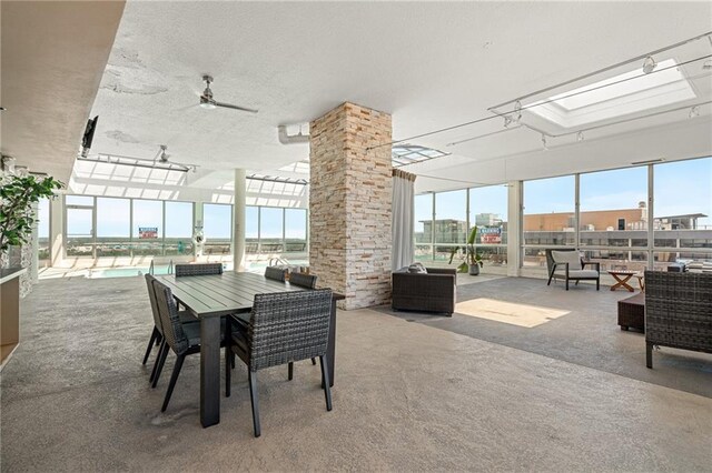 dining space with a textured ceiling, carpet floors, a skylight, and ceiling fan