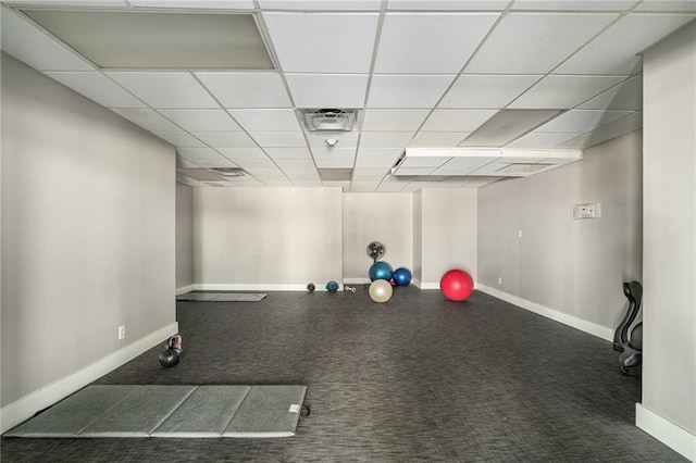 exercise room featuring a paneled ceiling and dark carpet