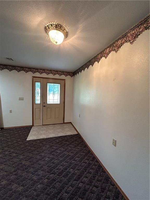 foyer entrance with a textured ceiling and light carpet