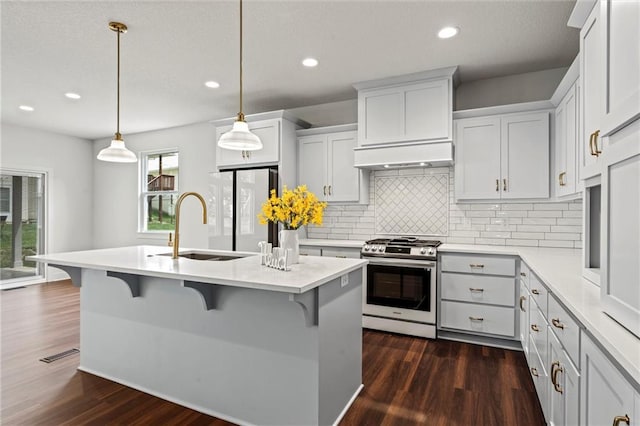 kitchen featuring a kitchen breakfast bar, stainless steel range with gas cooktop, decorative light fixtures, dark hardwood / wood-style flooring, and white cabinetry