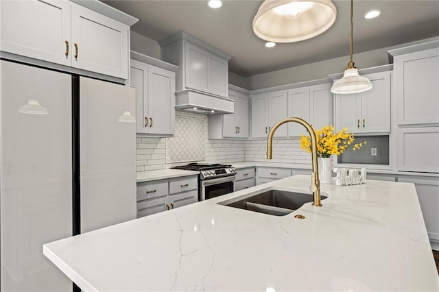 kitchen featuring backsplash, high end stove, decorative light fixtures, light stone counters, and custom range hood