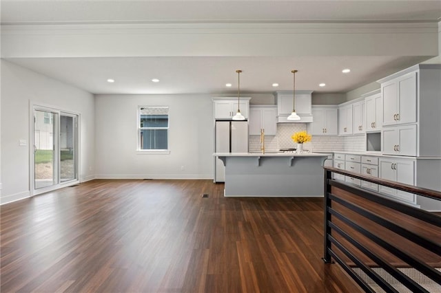 kitchen featuring a breakfast bar, a center island with sink, decorative light fixtures, dark hardwood / wood-style flooring, and white cabinetry