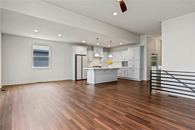 unfurnished living room featuring a healthy amount of sunlight, dark hardwood / wood-style flooring, and crown molding