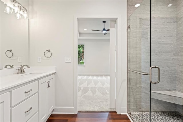 bathroom with hardwood / wood-style floors, ceiling fan, a shower with door, and vanity