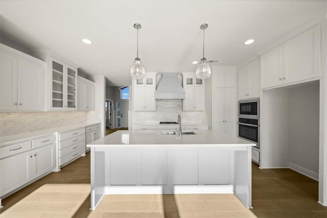 kitchen with built in microwave, stainless steel oven, light hardwood / wood-style floors, white cabinets, and custom exhaust hood