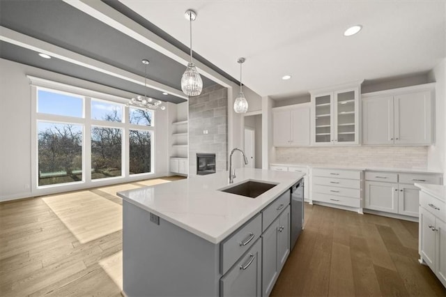 kitchen featuring sink, tasteful backsplash, stainless steel dishwasher, an island with sink, and light hardwood / wood-style floors