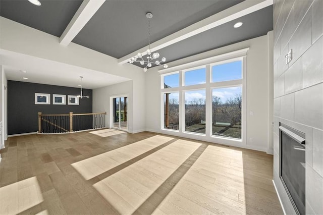 unfurnished living room with a large fireplace, wood-type flooring, and an inviting chandelier