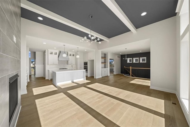 unfurnished living room with a fireplace, sink, dark hardwood / wood-style flooring, and an inviting chandelier