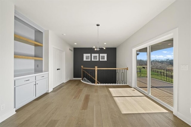 unfurnished dining area featuring an inviting chandelier and light wood-type flooring