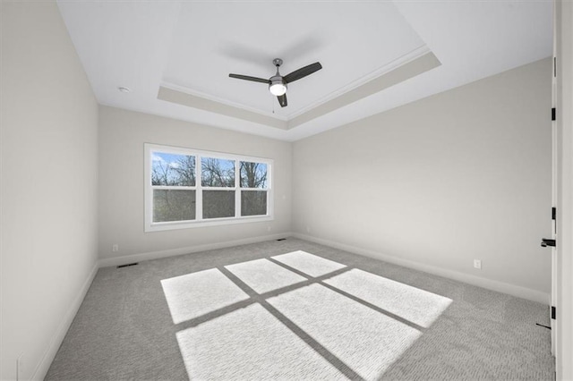 carpeted spare room featuring ceiling fan, crown molding, and a tray ceiling