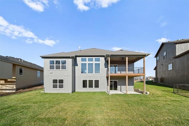 back of property with a yard, a balcony, and ceiling fan