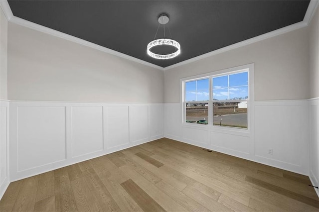 empty room with light wood-type flooring and crown molding