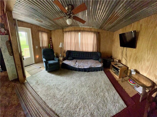 living area with wooden walls, carpet floors, and ceiling fan