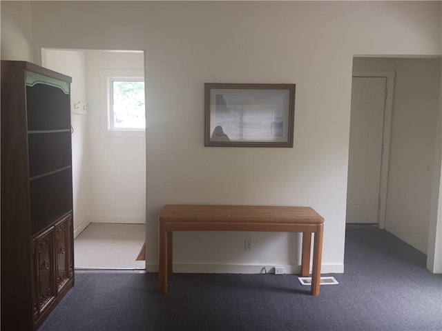 hall featuring dark colored carpet