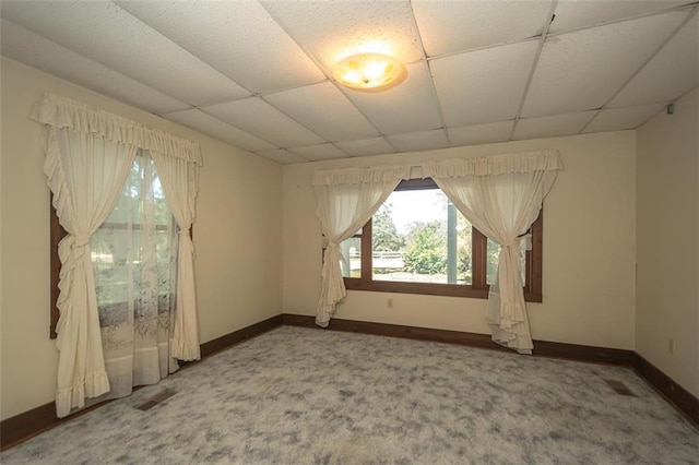 empty room with carpet and a paneled ceiling