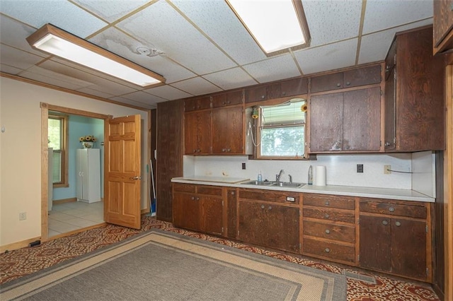 kitchen with light tile patterned floors, dark brown cabinetry, and sink