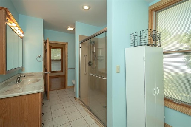 bathroom featuring tile patterned floors, vanity, toilet, and an enclosed shower