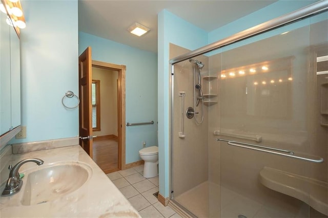 bathroom featuring tile patterned flooring, vanity, toilet, and an enclosed shower