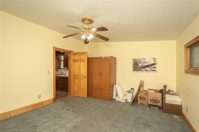 unfurnished bedroom with ceiling fan, sink, dark carpet, and a textured ceiling