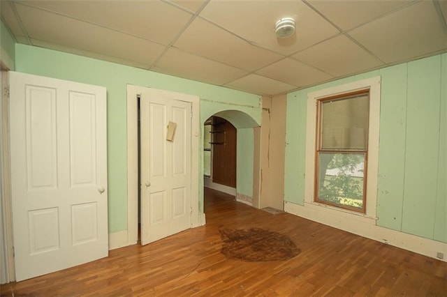 empty room with a drop ceiling and wood-type flooring