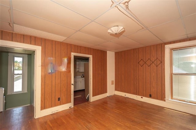 unfurnished room with wood-type flooring, a paneled ceiling, and wood walls