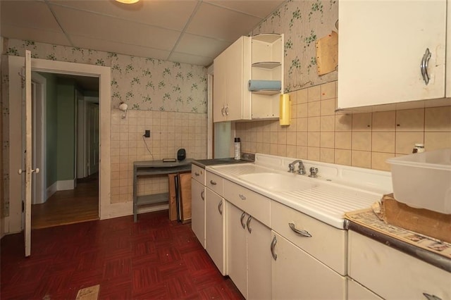 kitchen featuring a paneled ceiling, dark parquet floors, sink, tile walls, and white cabinetry