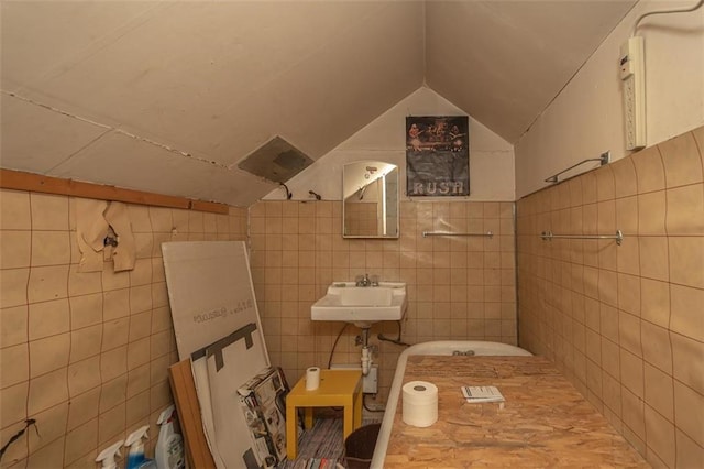 bathroom with tile walls, lofted ceiling, and sink