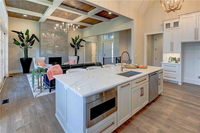 kitchen featuring beamed ceiling, coffered ceiling, hardwood / wood-style floors, and a kitchen island with sink