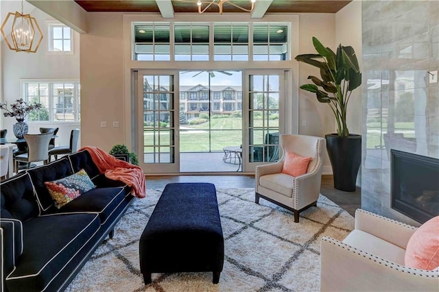 living room featuring hardwood / wood-style floors, a fireplace, a notable chandelier, and beam ceiling