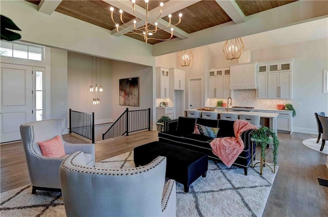 living room with a chandelier, sink, beam ceiling, light hardwood / wood-style flooring, and wood ceiling