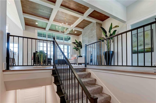 staircase with beam ceiling, a high ceiling, an inviting chandelier, wood ceiling, and coffered ceiling