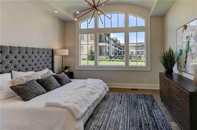 bedroom with an inviting chandelier, dark hardwood / wood-style flooring, and a towering ceiling