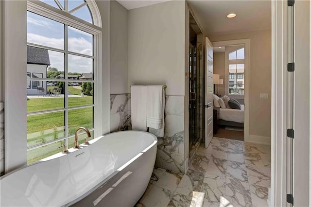 bathroom with tile patterned flooring, tile walls, and a tub to relax in