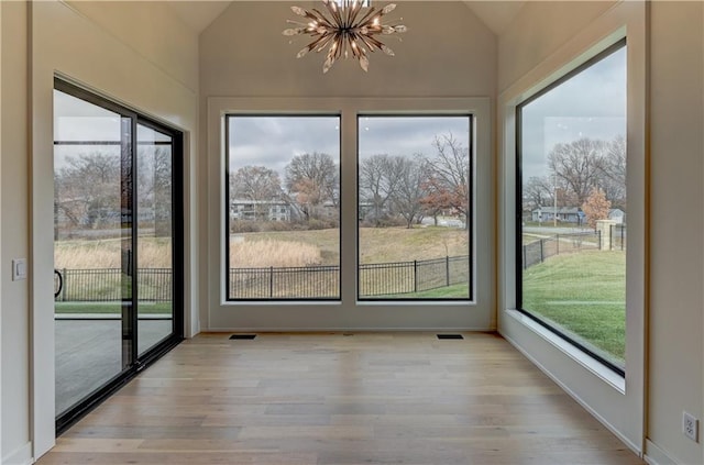 unfurnished sunroom featuring a notable chandelier, plenty of natural light, and lofted ceiling