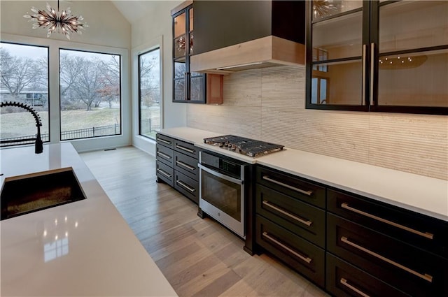 kitchen featuring backsplash, sink, light hardwood / wood-style flooring, wall chimney exhaust hood, and stainless steel appliances