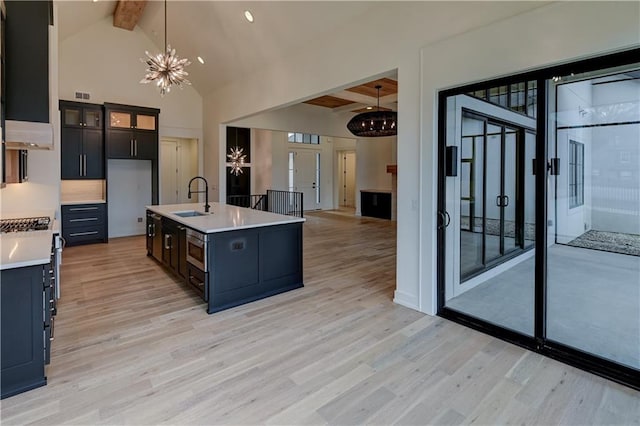 kitchen featuring an inviting chandelier, sink, light hardwood / wood-style floors, decorative light fixtures, and beam ceiling