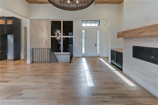 foyer featuring a tile fireplace, a chandelier, a high ceiling, and light wood-type flooring