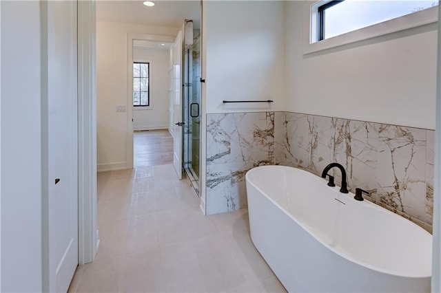 bathroom with tile patterned flooring, shower with separate bathtub, plenty of natural light, and tile walls