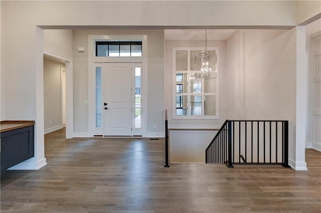 entryway with dark hardwood / wood-style floors, a wealth of natural light, and a notable chandelier