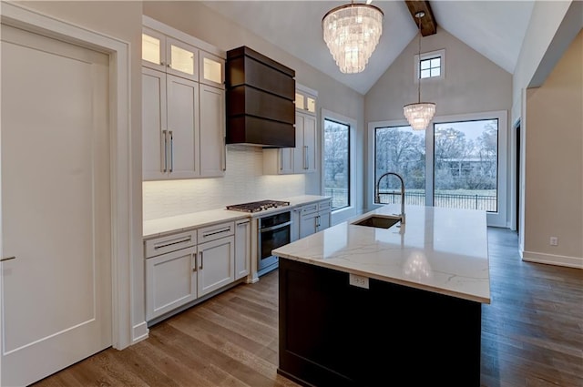 kitchen featuring a notable chandelier, sink, hanging light fixtures, and an island with sink